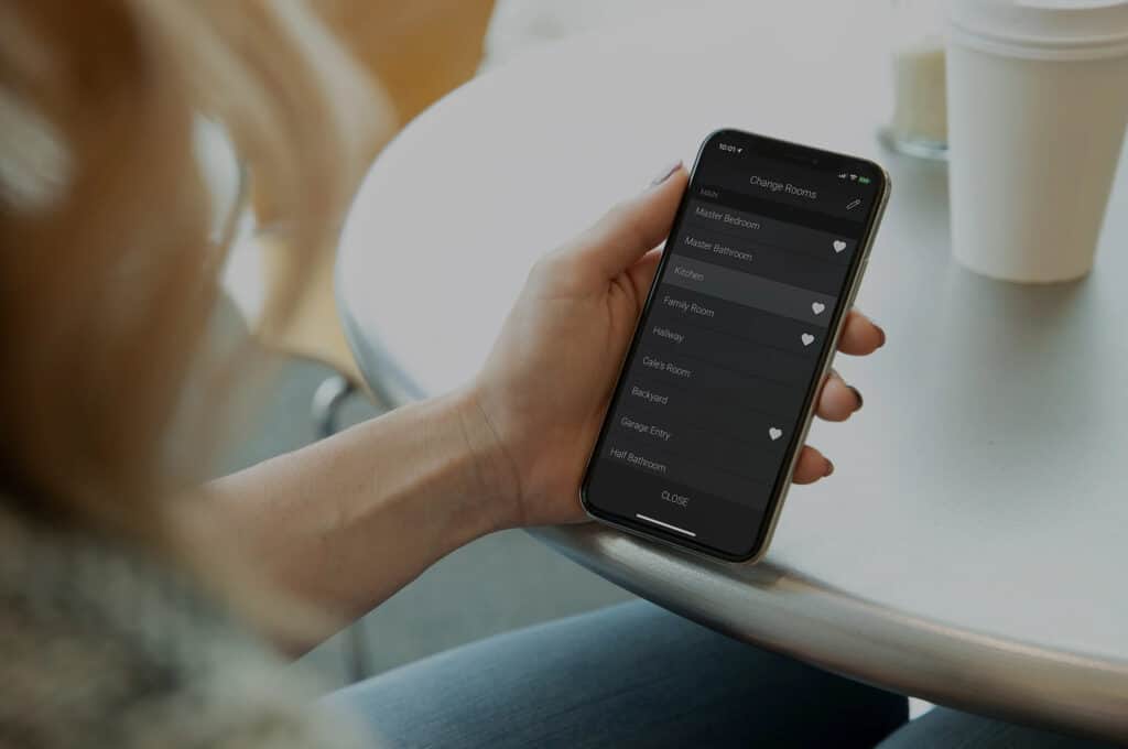 Woman using the Control4 app on her smart phone to control each room in her house